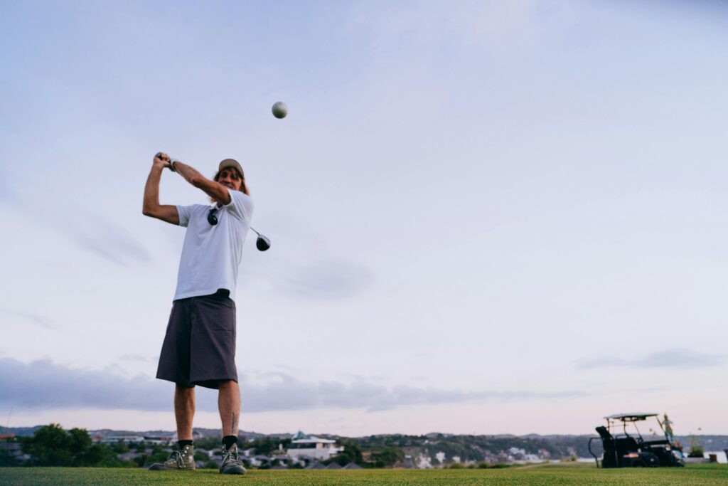 A man swinging a golf club on a scenic outdoor course during the evening.